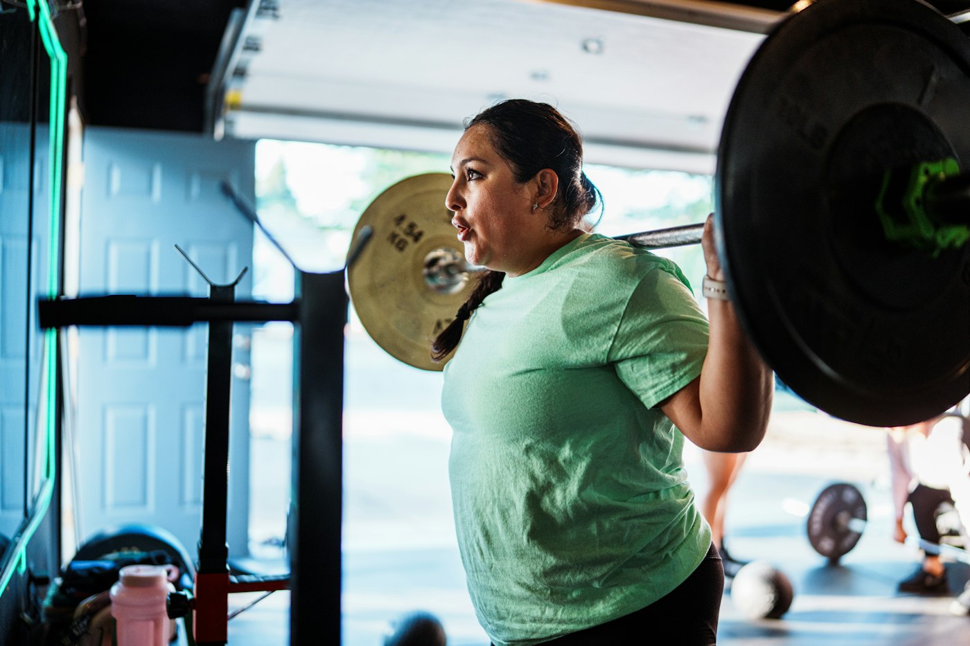 Femme en squat avec une barre chargée
